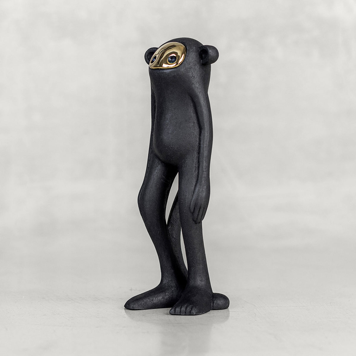 Quarter view of a black monkey figurine with a brass face on a white background