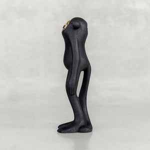 Side view of a black monkey figurine with a brass face on a white background