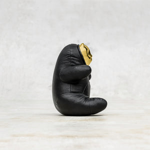 Side view of a black leather BLamo toy with brass face 