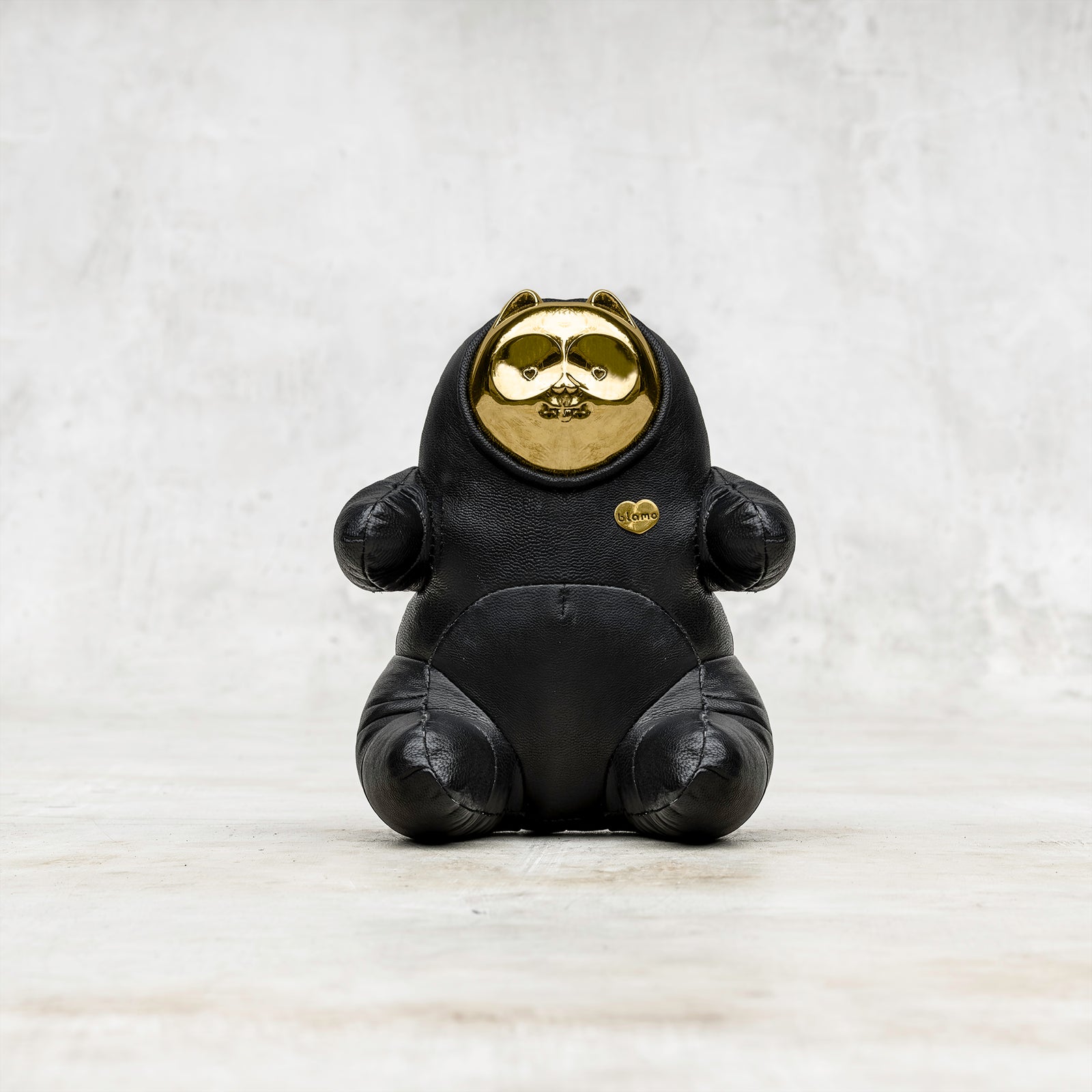 A Blamo Bubs gold brass and black leather animal toy figurine sitting on a gray surface 