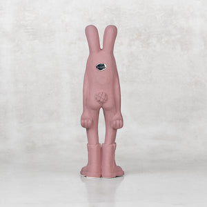 Back view of a ceramic lavender bunny statuette against a light gray background