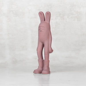 Ceramic lavender bunny statuette with brass eyes facing sideways against a light gray background