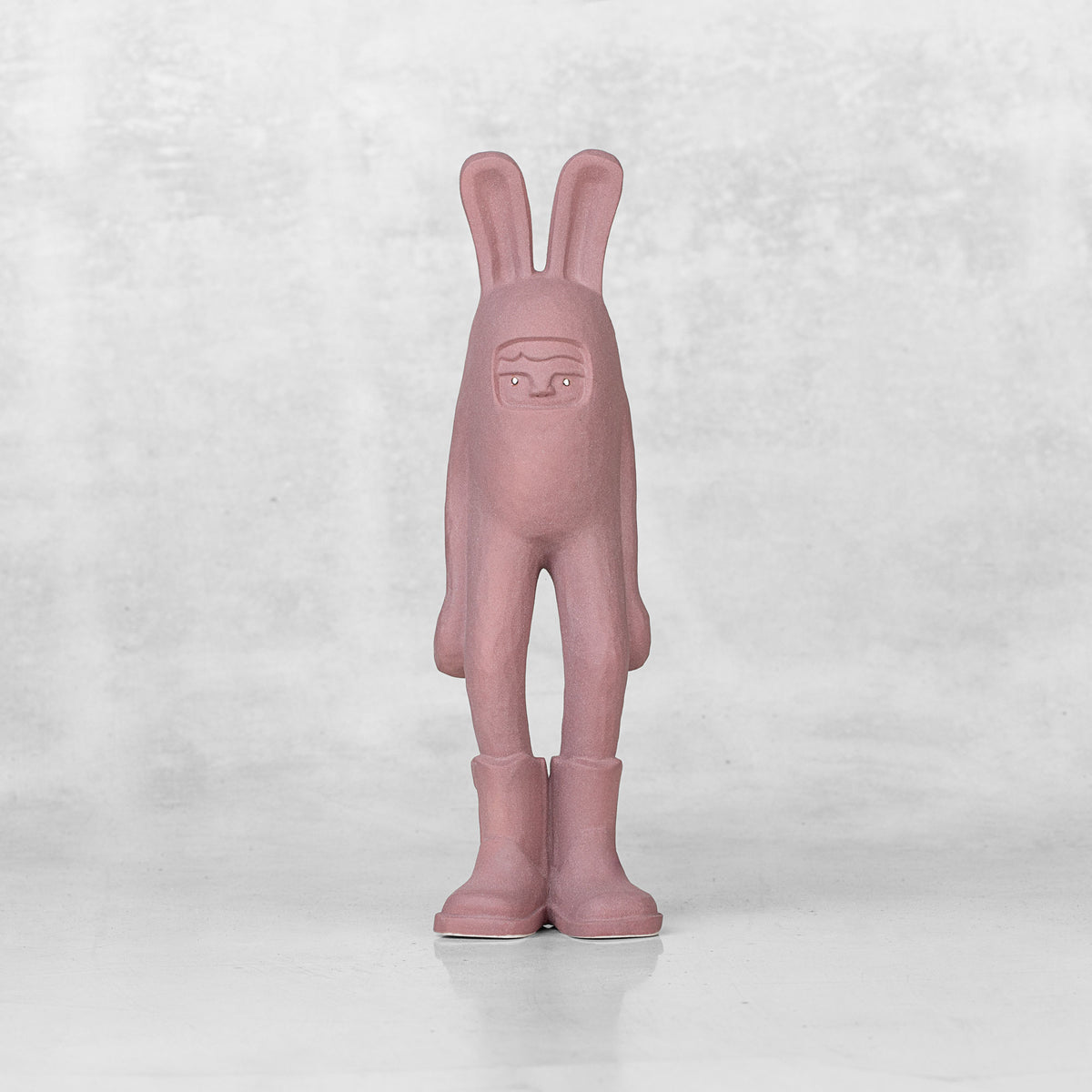 Ceramic lavender bunny statuette with brass eyes against a light gray background