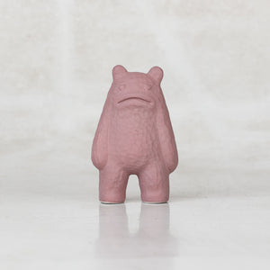 Ceramic lavender creatures with heart eyes frowning against a light gray background