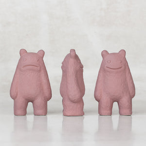 3 Ceramic lavender creatures with faces on the front and back sides of their heads facing different directions against a light gray background