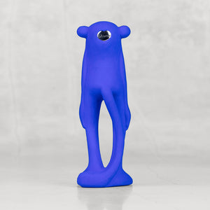 Back view of a blue monkey statuette with a silver heart emblem against a light gray background