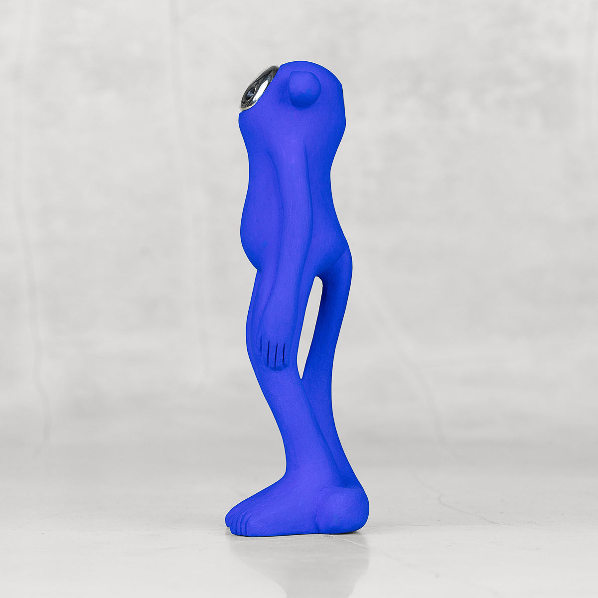 Side view of a blue monkey statuette with a silver face against a light gray background