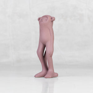 Quarter view of a lavender ceramic monkey statuette with brass eyes against a light gray background
