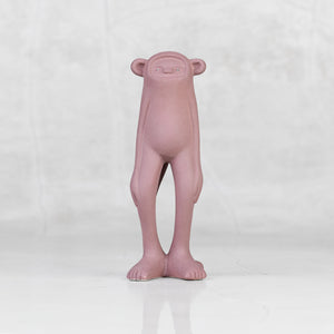 Lavender ceramic monkey statuette with brass eyes against a light gray background