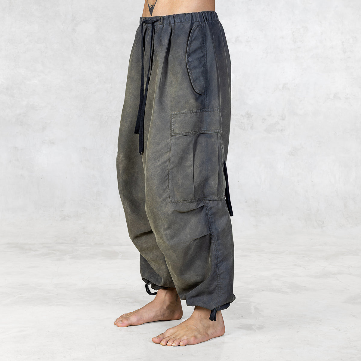 Person wearing hand painted olive oversized raver-style pants on a white background