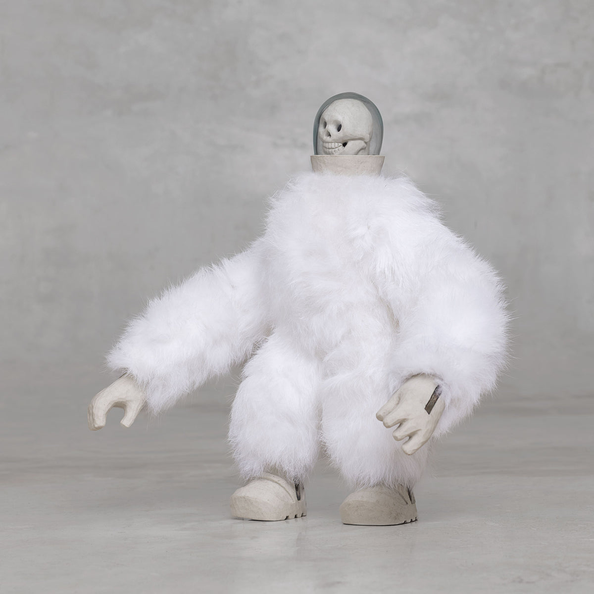 White furry creature statue with skull head against a light gray background 