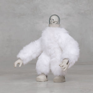 White furry creature statue with skull head against a light gray background 