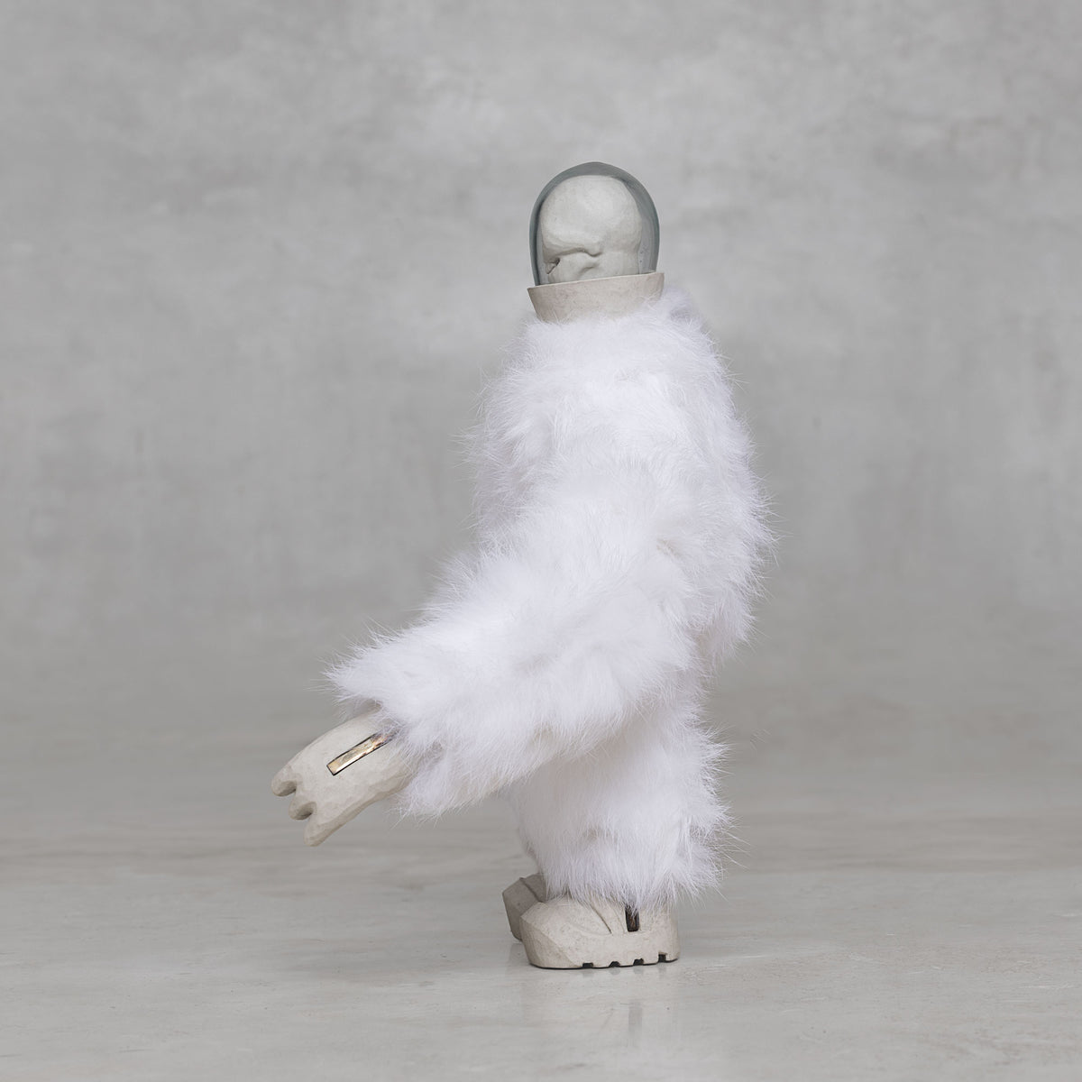 Side view of a white furry creature statue against a light gray background 