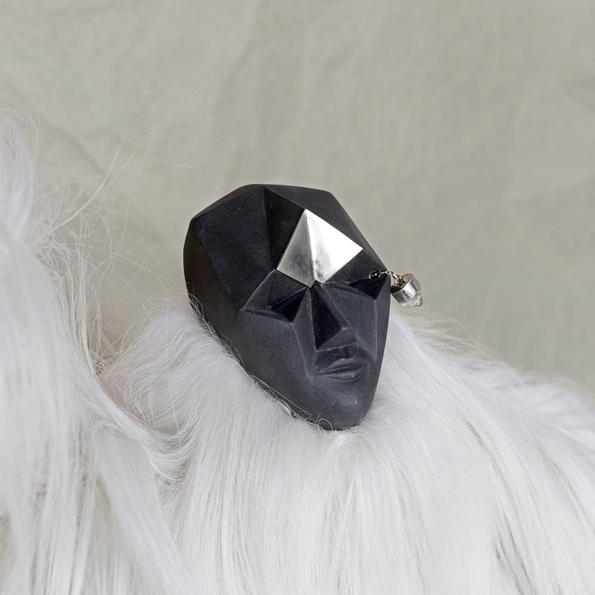 Ceramic fur and brass creature sculpture against a beige background