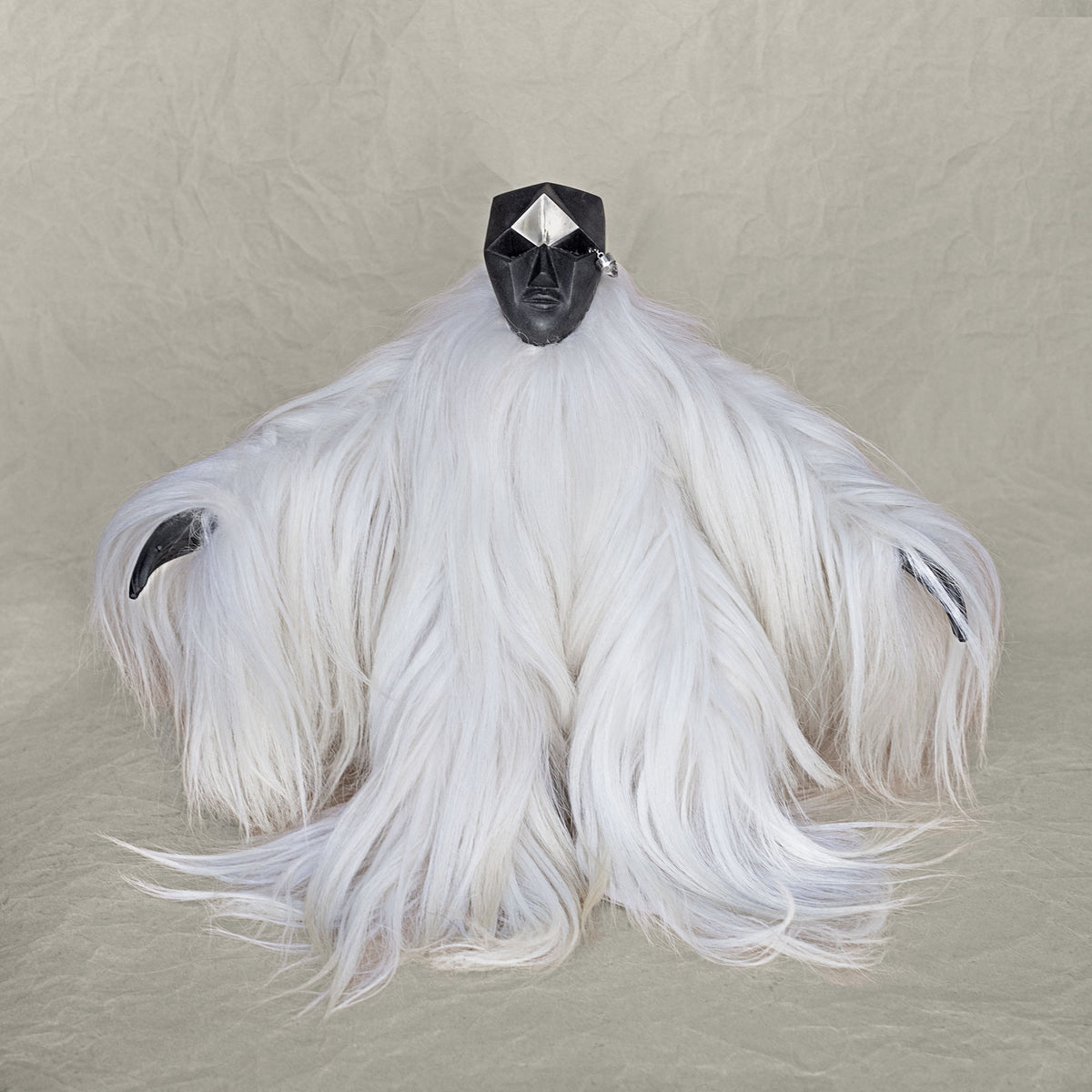 Ceramic fur and brass creature sculpture standing against a beige background