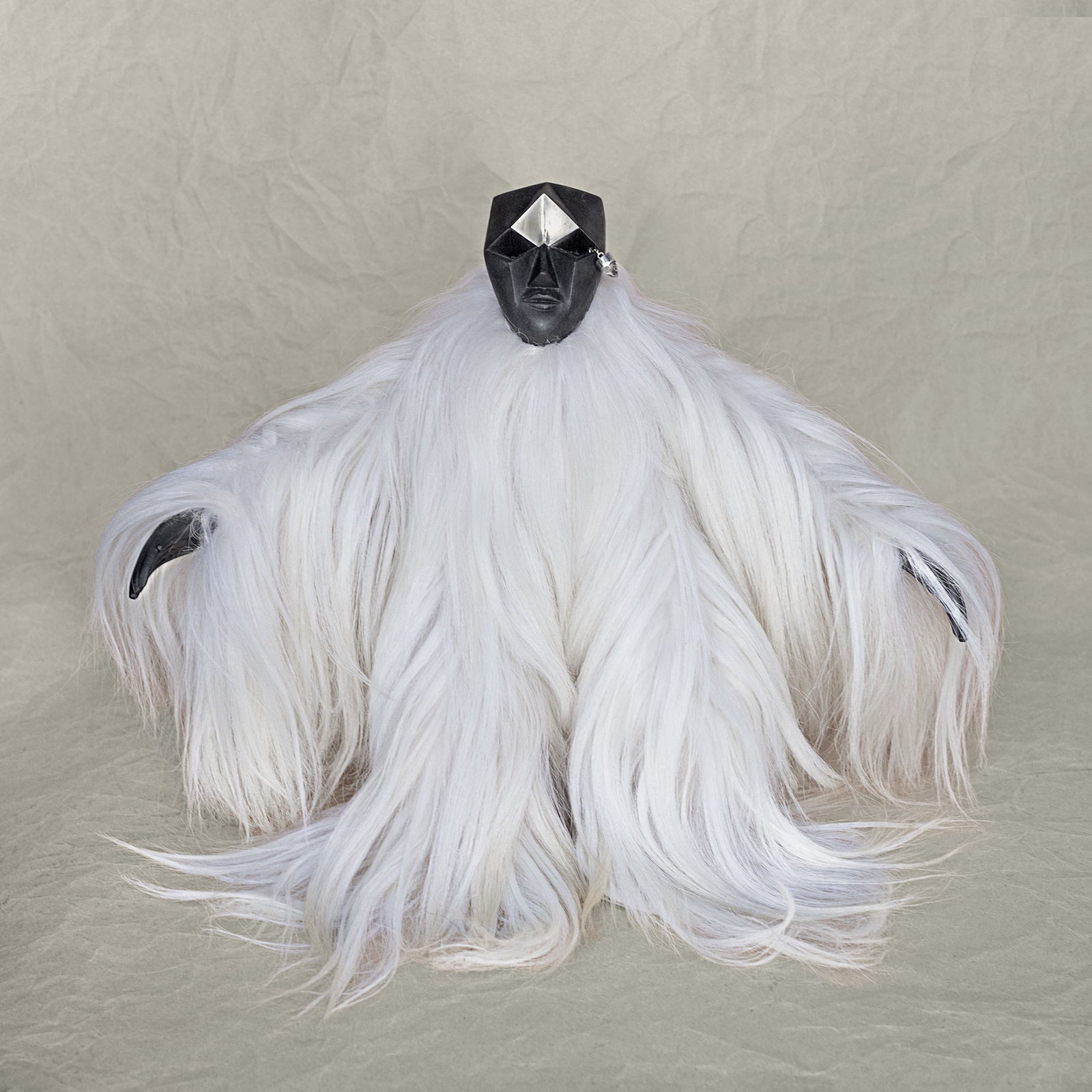 Ceramic fur and brass creature sculpture standing against a beige background