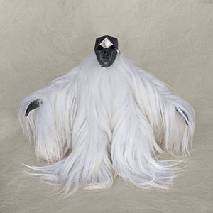 Ceramic fur and brass creature sculpture standing against a beige background
