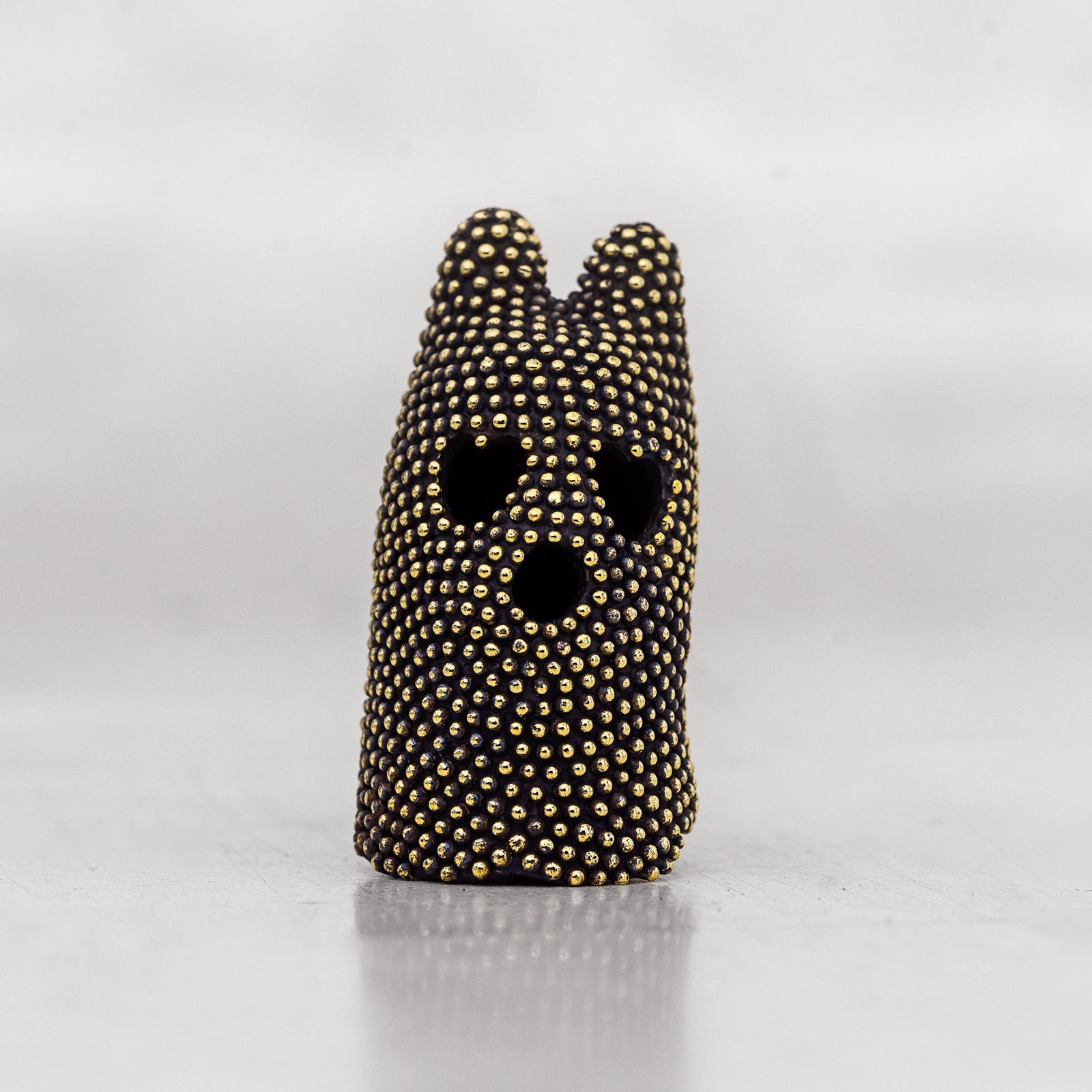 Black and gold brass mask object on a white surface