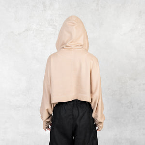 The back of a model shown from the waist up wearing a fog colored cropped French terry Daydreamer Hoodie with long arms and thumb holes. 