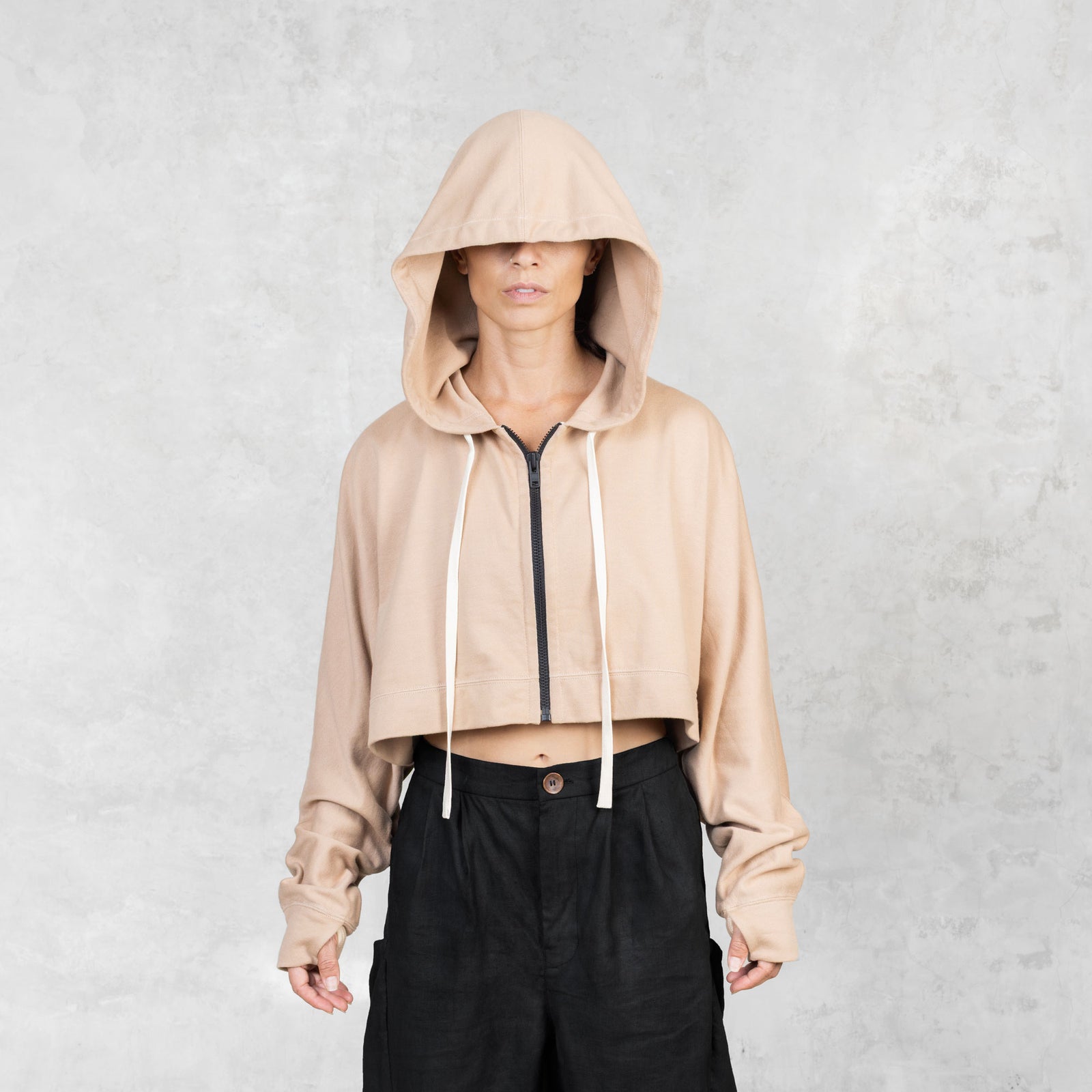 Model shown from the waist up wearing a fog colored cropped French terry Daydreamer Hoodie with a black contrast zipper and white drawstring.

