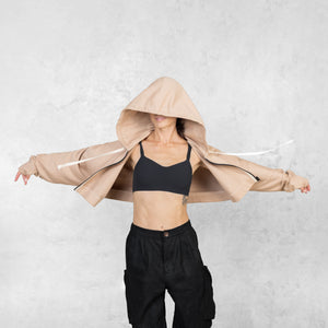 Model with arms extended in motion from the waist up wearing a fog colored cropped French terry Daydreamer Hoodie with a black contrast zipper and white drawstring.