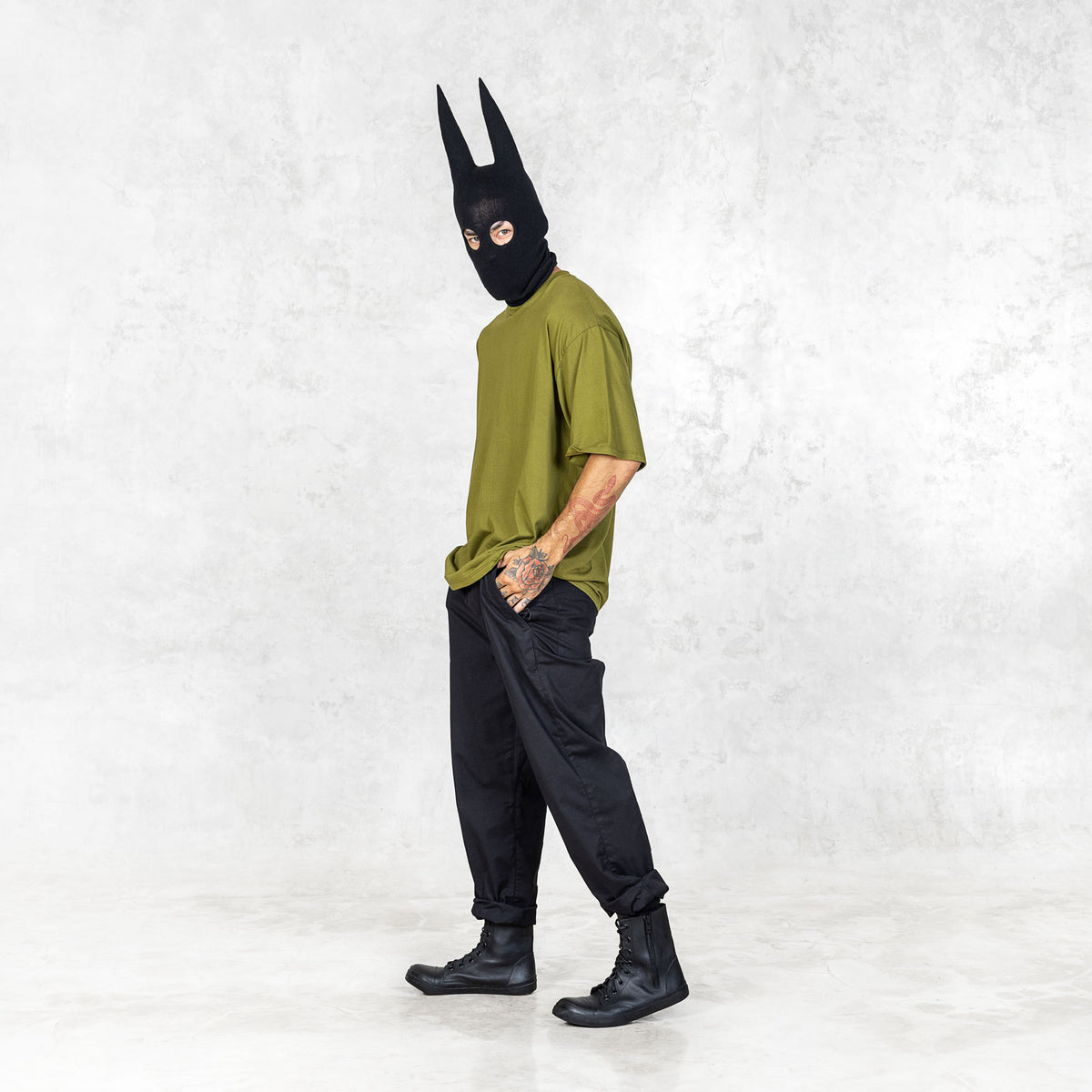 Person wearing a black mask and green shirt against a white background