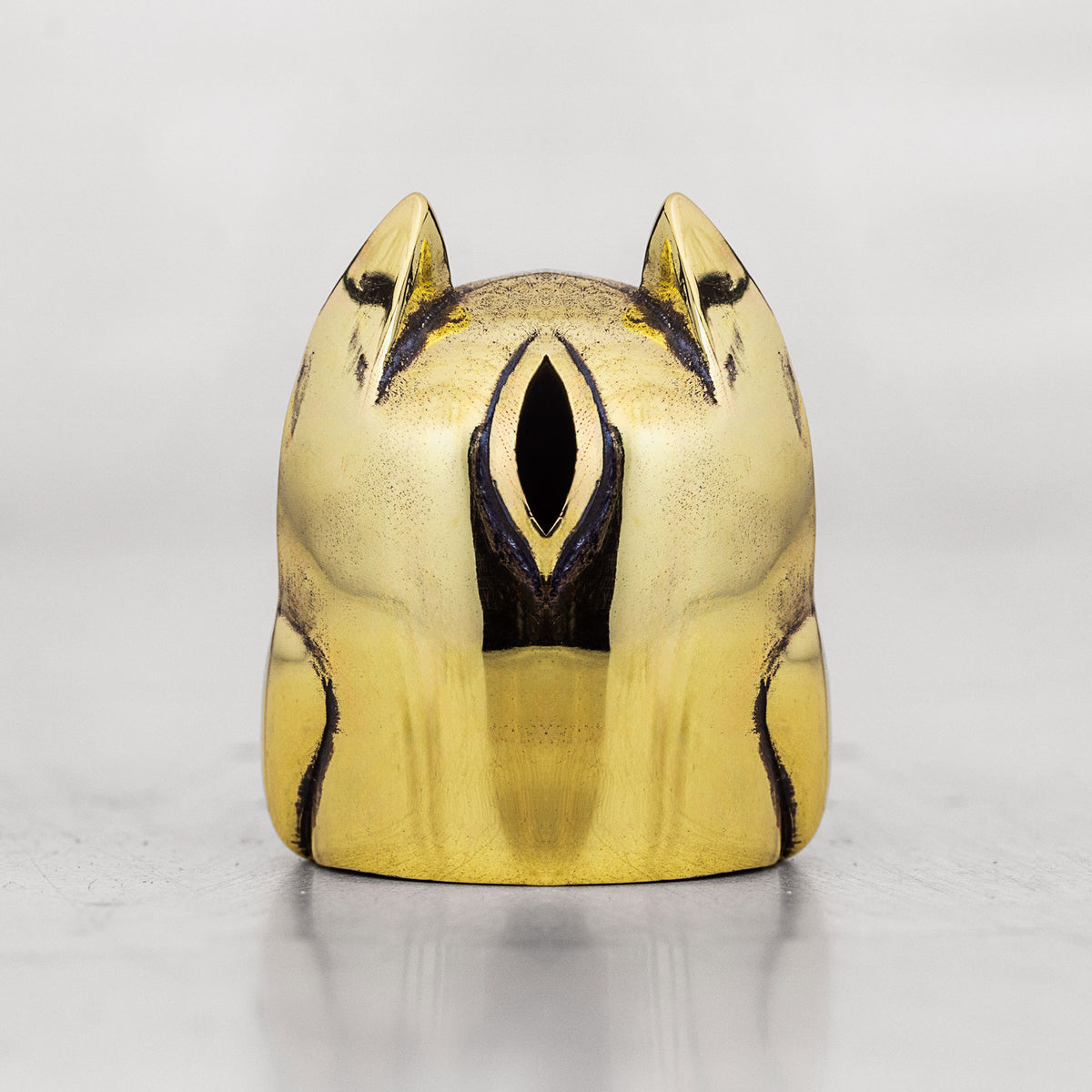 Brass cat-shaped object with black accents on a white background