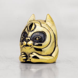 Gold brass cat-shaped object on a light gray background