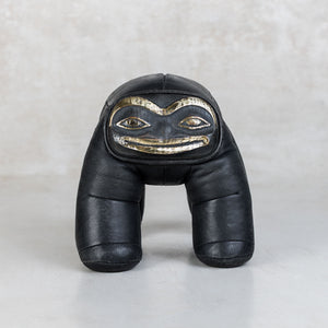Black leather toy with face design on a white background
