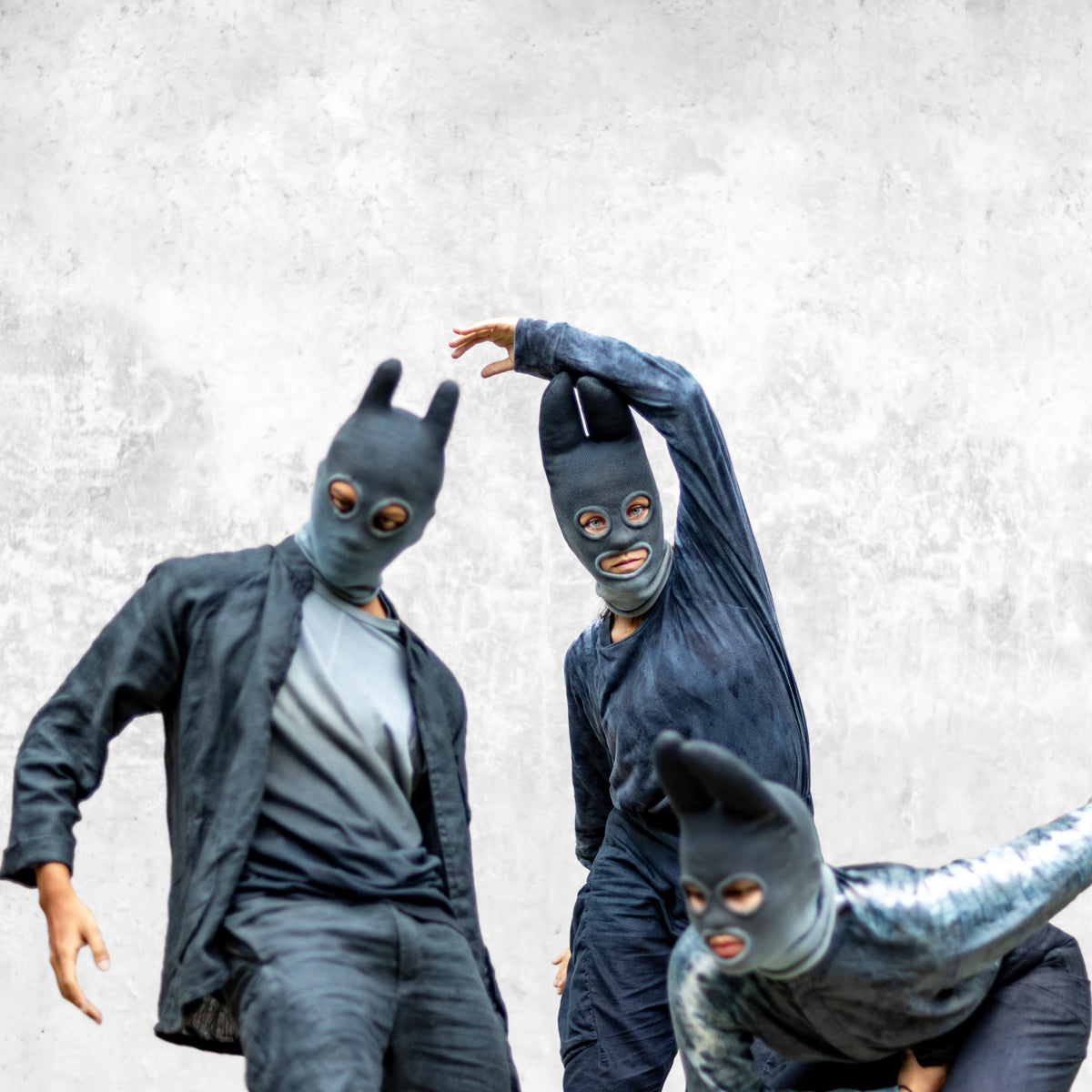Group of people wearing blue masks and outfit posing against a light gray background 