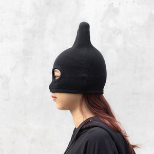 Person facing sideways wearing a black mask with ears on a light gray background