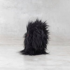 Black furry creature on a light gray background