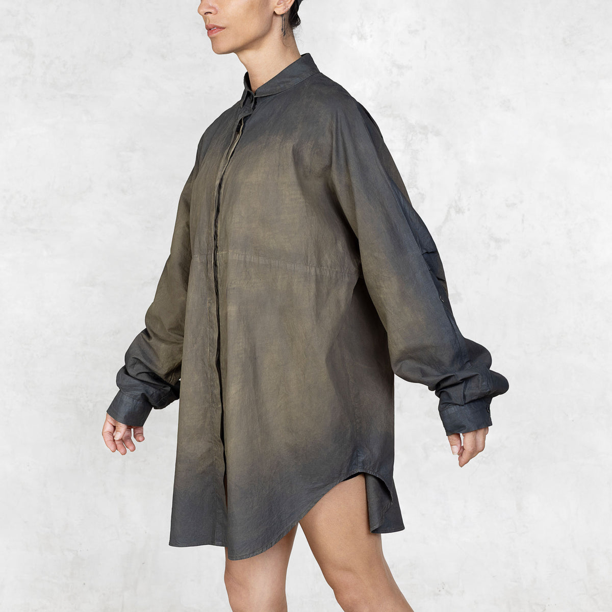 Side view of person wearing hand-painted olive tunic button up shirt against a white background