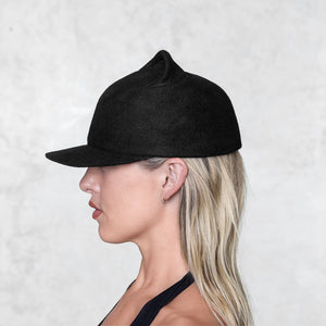 A profile of a woman wearing a small eared felt cap 