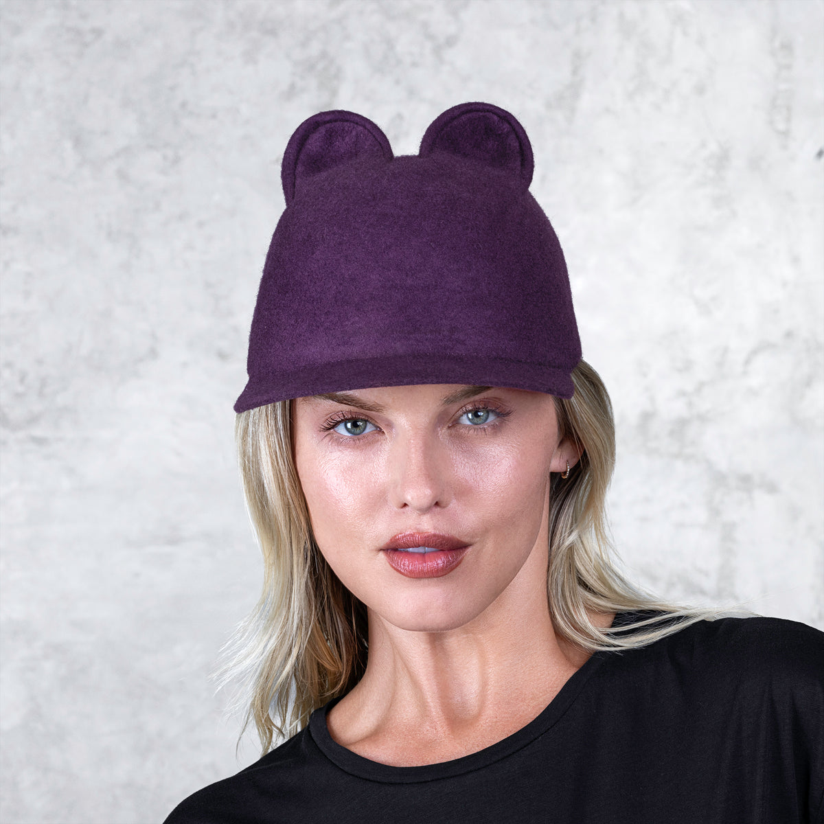 A profile of a woman wearing a small eared felt cap