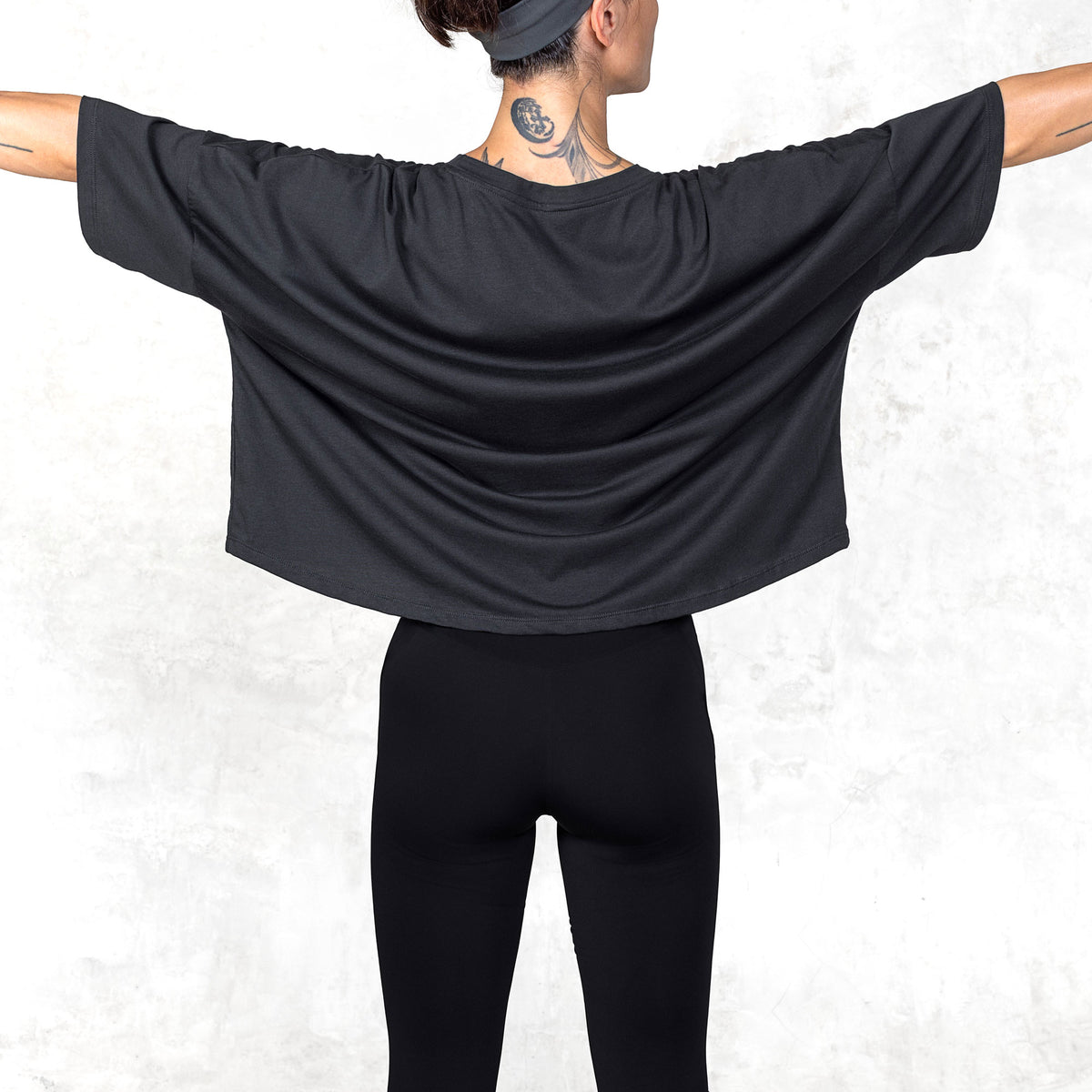 Waist-up view of model wearing Katana cropped Supima cotton tee with arms extended to show fit and drape.