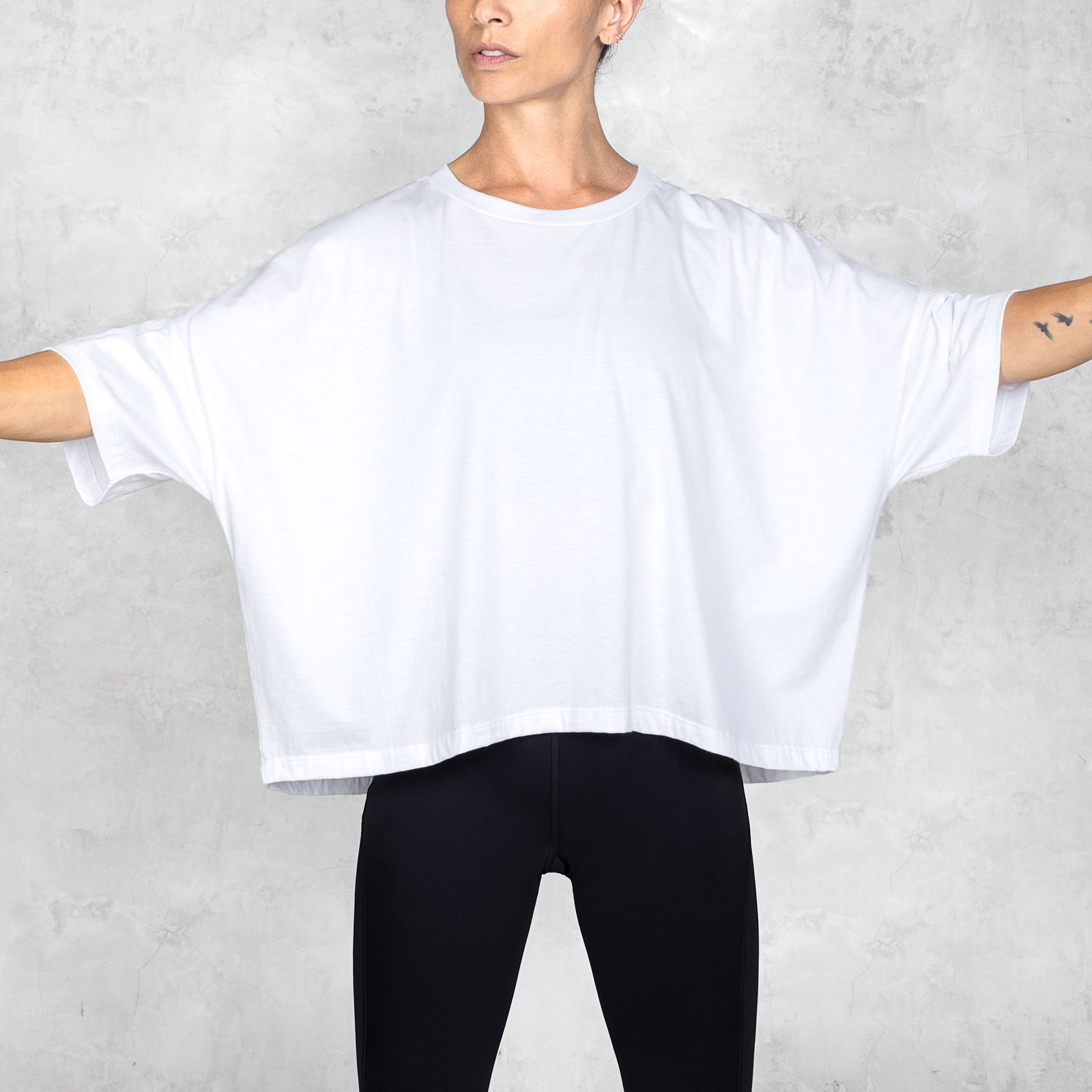 Person wearing a white oversized t-shirt and black pants against a white background