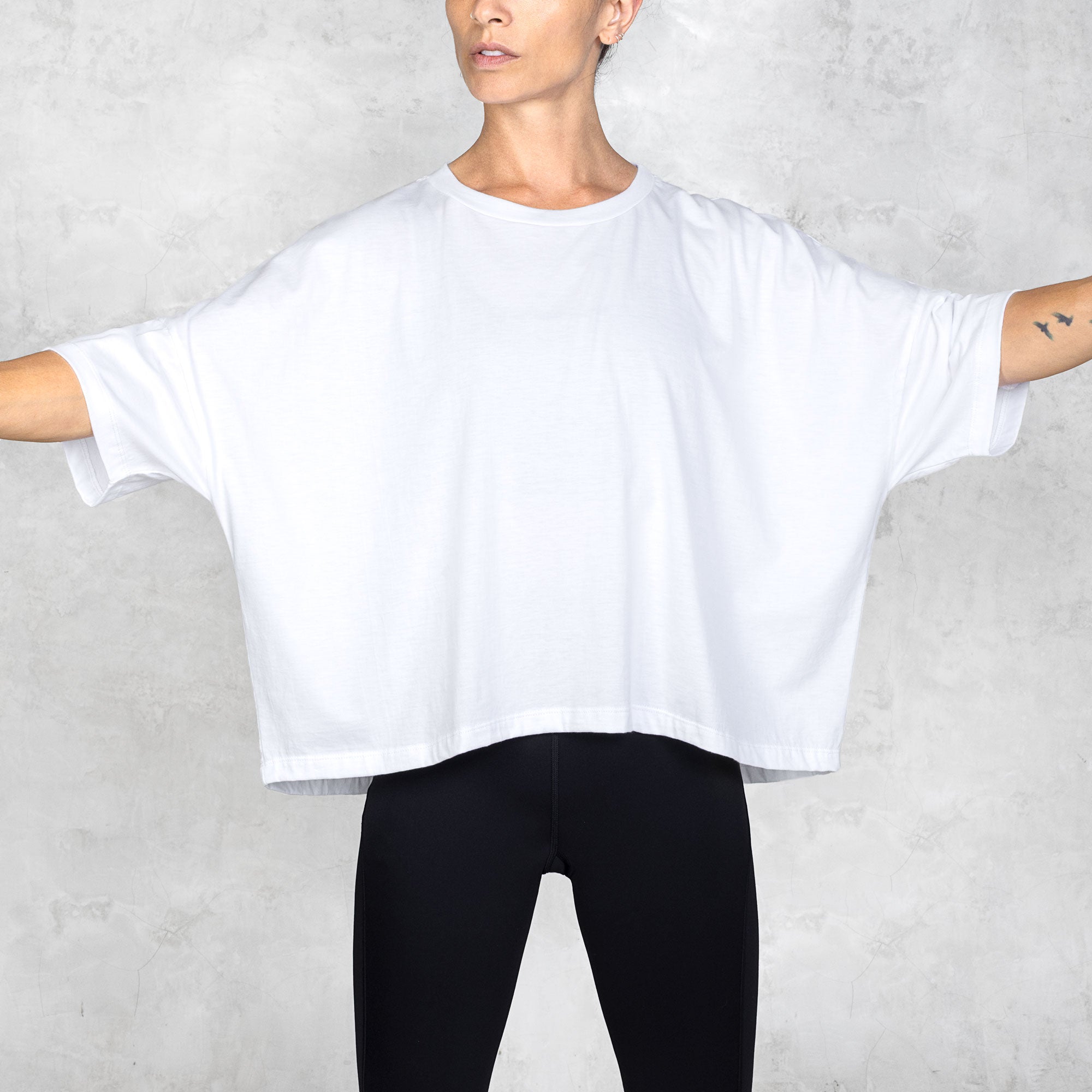 Person wearing a white oversized t-shirt and black pants against a white background