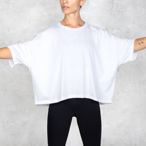 Person wearing a white oversized t-shirt and black pants against a white background