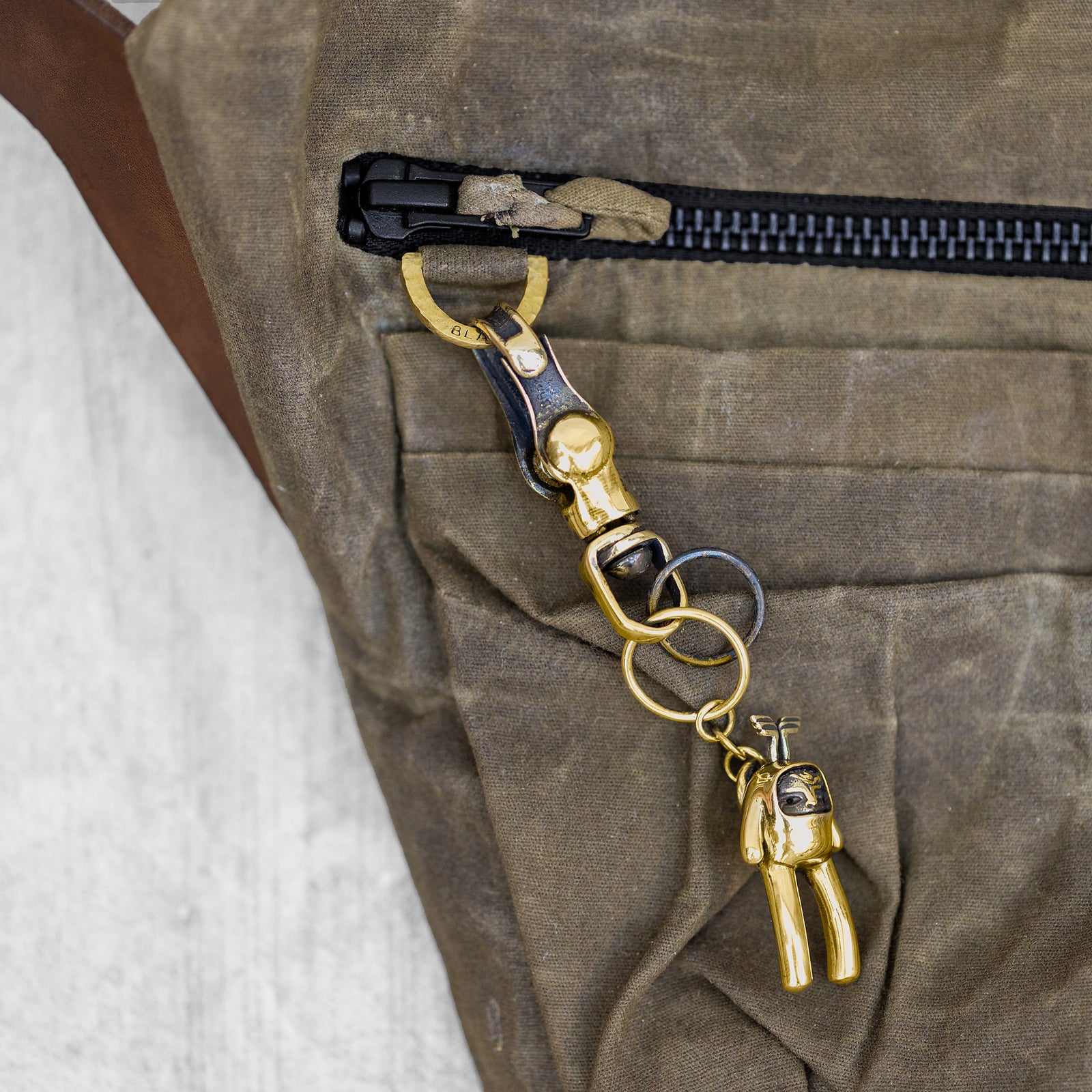 Close up of a D-ring keychain holder with a brass keychain attached on a fanny pack 