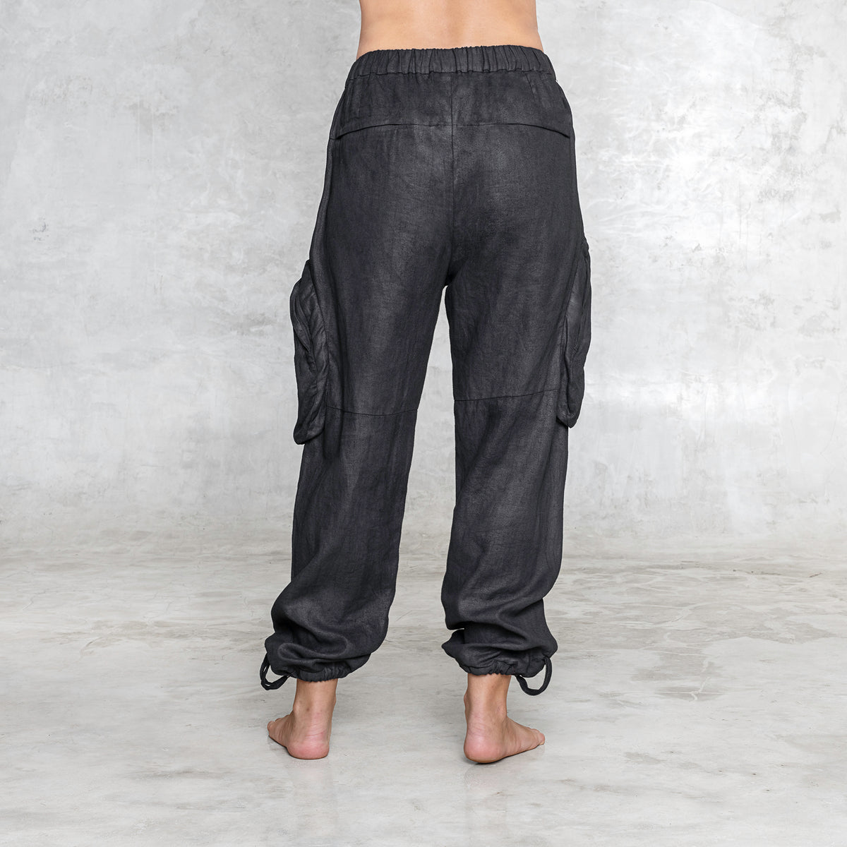 The back of a woman from waist down wearing black linen pants