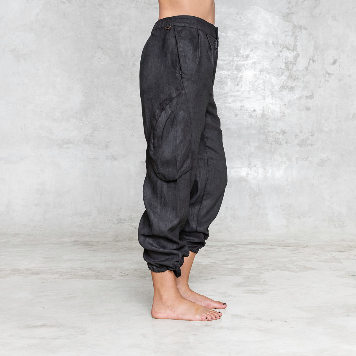 The side vew of a woman from waist down wearing black linen pants