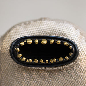 Close-up of a textured brass and leather creature.