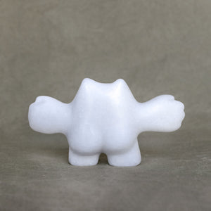 Back view of a white marble creature figurine with its arms outstretched against a gray background 