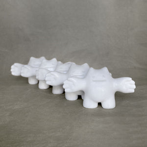 Group of small marble creature figurines with their arms stretched outwards against a gray background