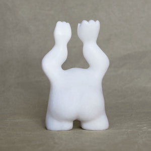 Back view of a small marble creature figurine with its arms raised above its head against a gray background