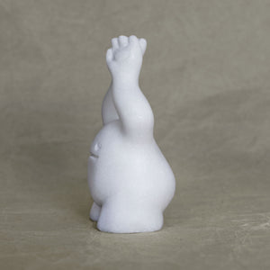 Side view of a small marble creature figurine with its arms raised above its head against a gray background