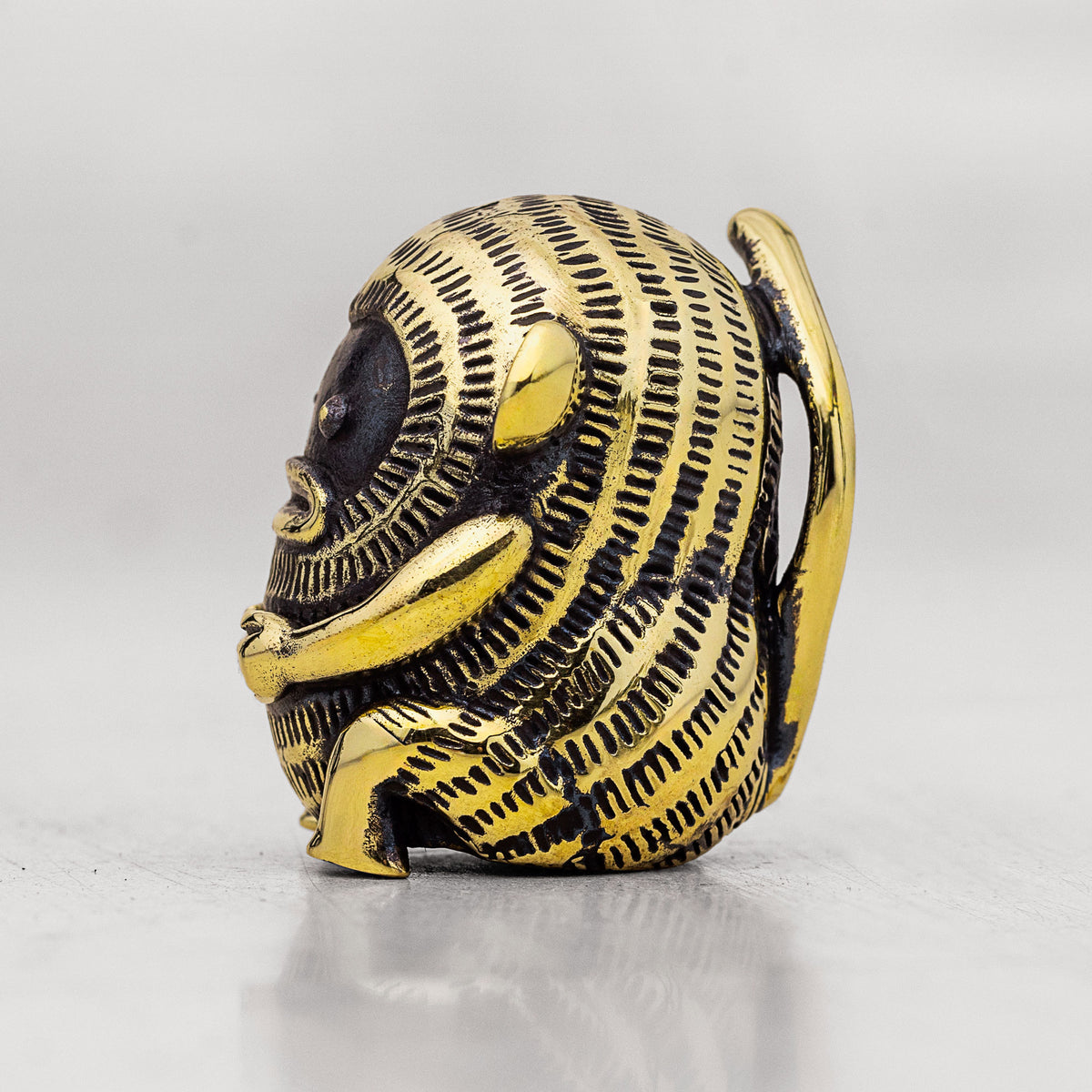 Gold and black brass monkey figurine with intricate design on a white background
