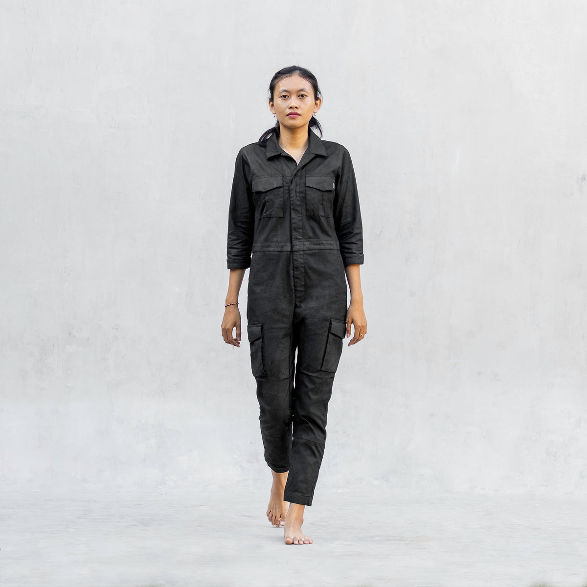 Woman walking forward in a one piece black walnut mechanic style BLAMO jumpsuit 