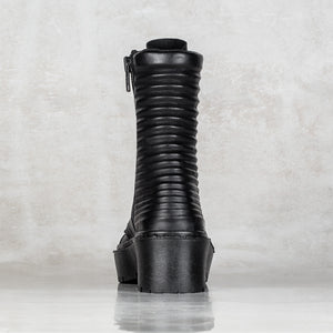 A single black mid-calf boot with a vertically ribbed shaft and a chunky platform sole, shown from the back against a textured light gray background.